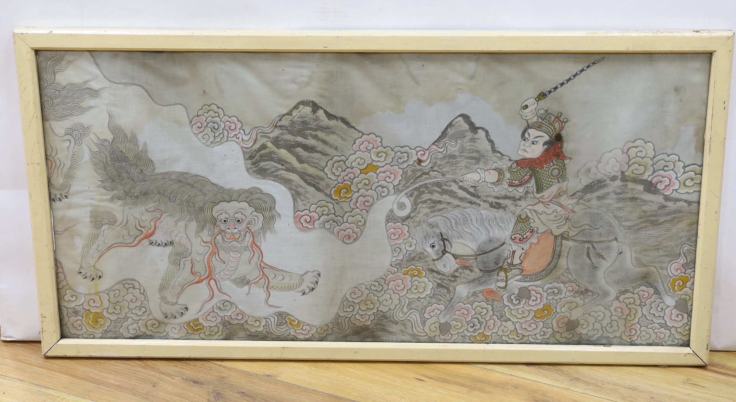 A framed Chinese silk study depicting a solider on horseback executing a dragon in stance, 49 x 104cm